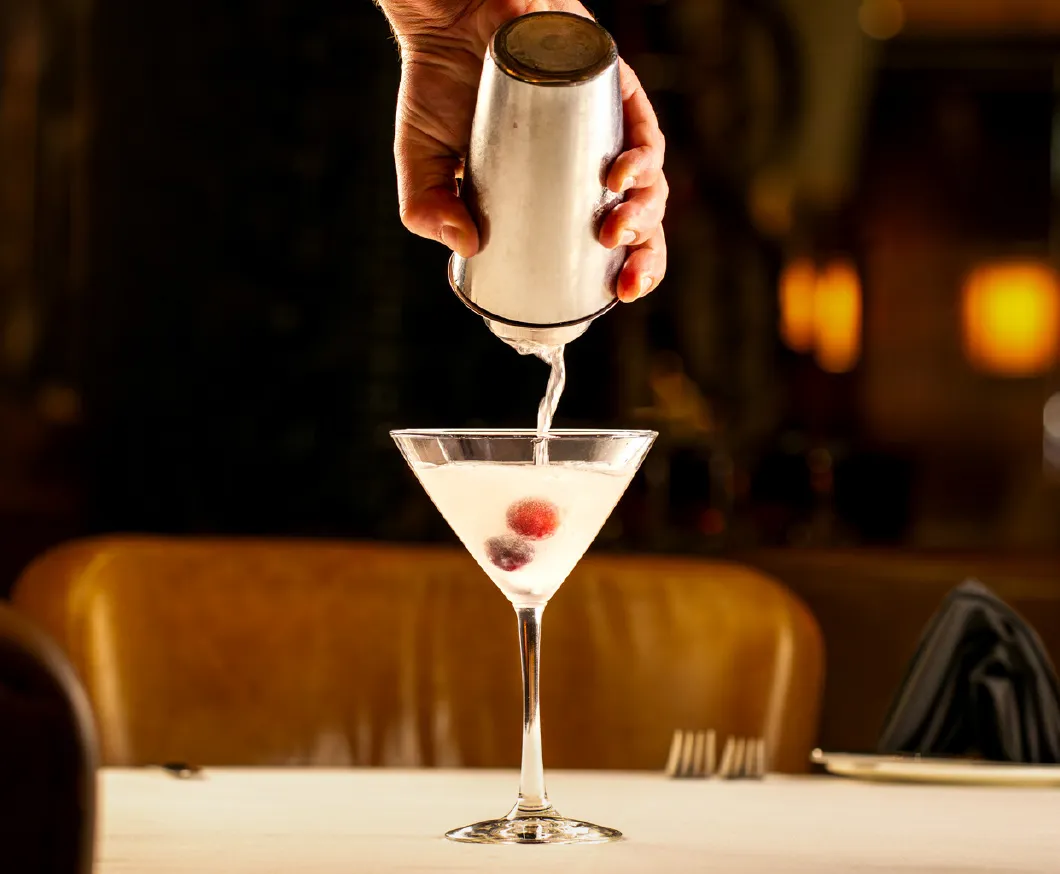A bartender pouring a martini